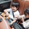 Child safely secured in a portable booster seat while traveling by car with family
