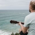 Beginner playing a travel guitar outdoors enjoying portable and comfortable music practice