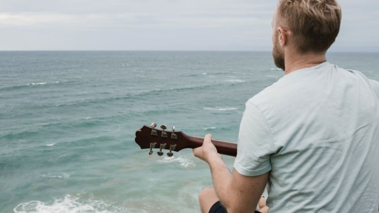 Beginner playing a travel guitar outdoors enjoying portable and comfortable music practice