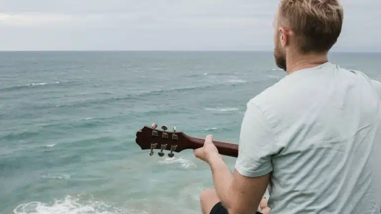 Beginner playing a travel guitar outdoors enjoying portable and comfortable music practice