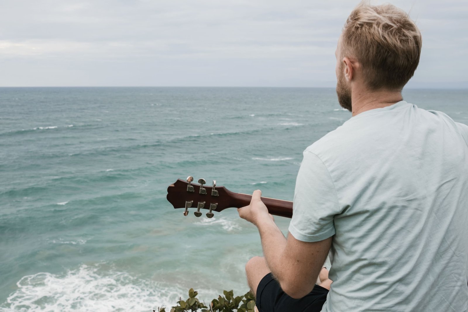 Beginner playing a travel guitar outdoors enjoying portable and comfortable music practice