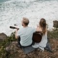Musician playing a compact Donner travel guitar outdoors, highlighting portability and sound quality for traveling musicians
