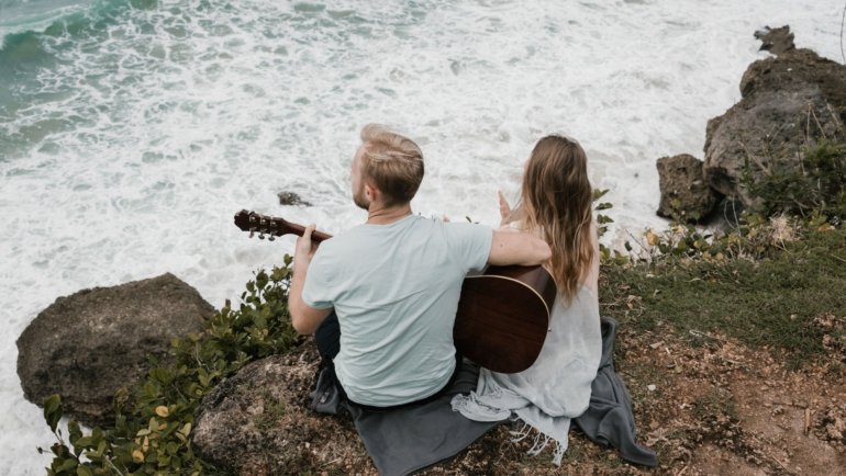 Musician playing a compact Donner travel guitar outdoors, highlighting portability and sound quality for traveling musicians
