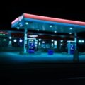 24 seven travel plaza at night with fuel stations, convenience store, and resting travelers on a highway road trip