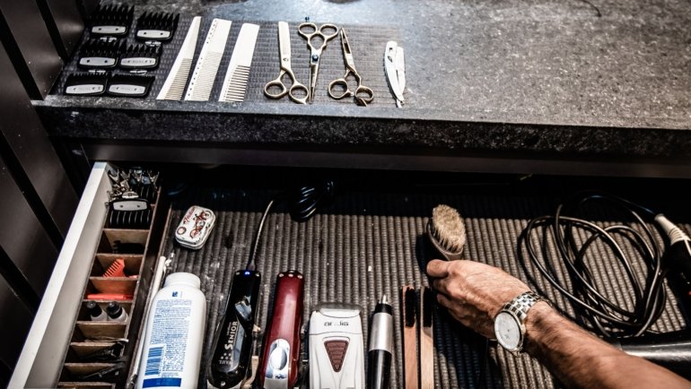 Close-up of a professional barber travel case with organized grooming tools including clippers, scissors, and combs