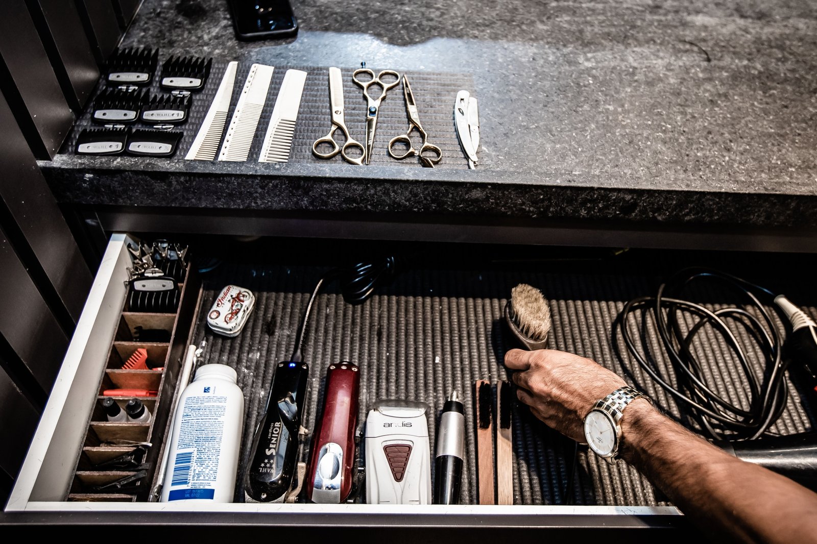 Close-up of a professional barber travel case with organized grooming tools including clippers, scissors, and combs