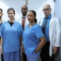 Cardiovascular travel nurse assisting with cardiac catheterization procedure in hospital cath lab
