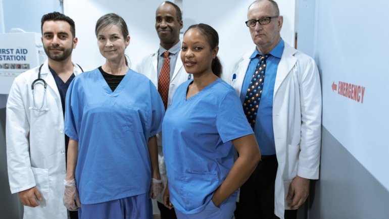 Cardiovascular travel nurse assisting with cardiac catheterization procedure in hospital cath lab
