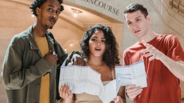 Young travel host guiding students in a vibrant city, sharing budget-friendly travel tips and cultural insights
