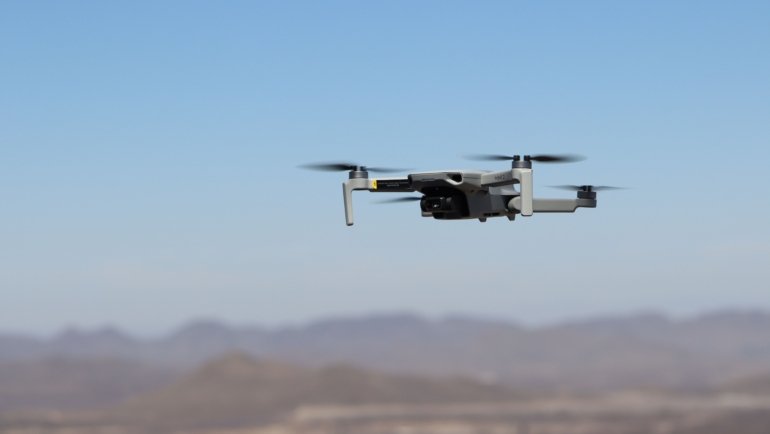Compact travel drone flying over scenic landscape capturing aerial photos and videos for travelers