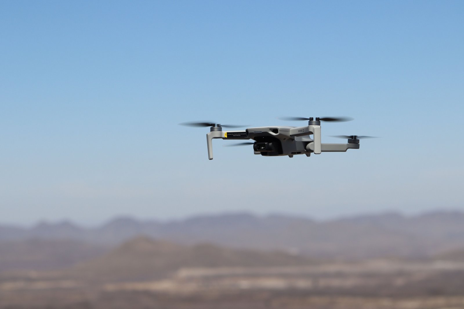 Compact travel drone flying over scenic landscape capturing aerial photos and videos for travelers