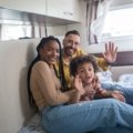 Happy family with travel trailer on a scenic road trip representing flexible buy here pay here travel trailer financing