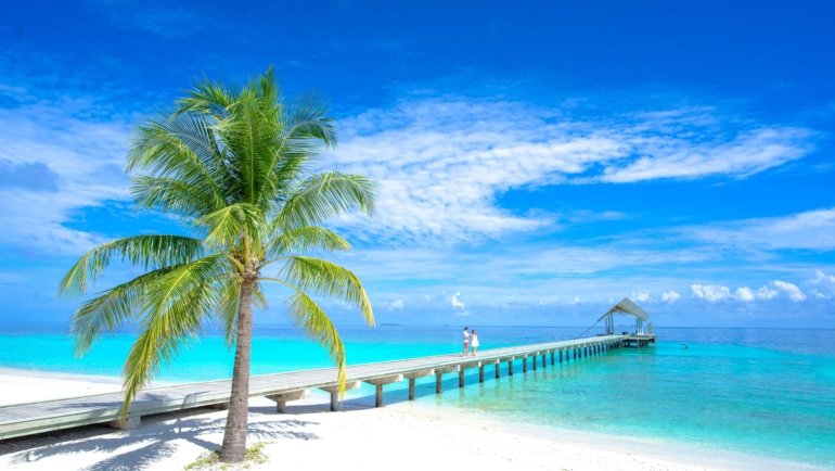 Sunny tropical beach in Tahiti with clear blue skies and turquoise water during the dry season