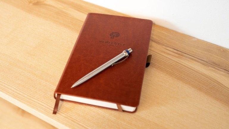 Leather bound travel diary open with pen on wooden table, symbolizing durable and stylish travel journaling companion
