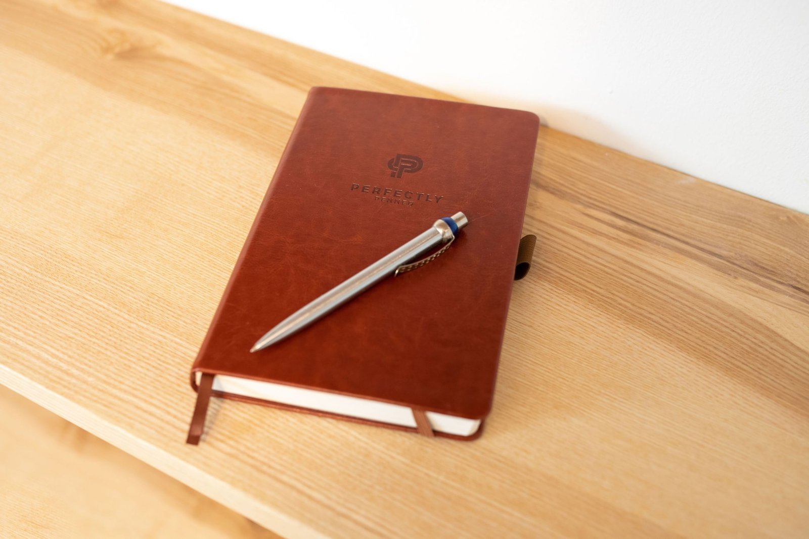 Leather bound travel diary open with pen on wooden table, symbolizing durable and stylish travel journaling companion