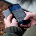Traveler checking smartphone data usage outdoors to manage mobile internet while navigating and communicating during trip