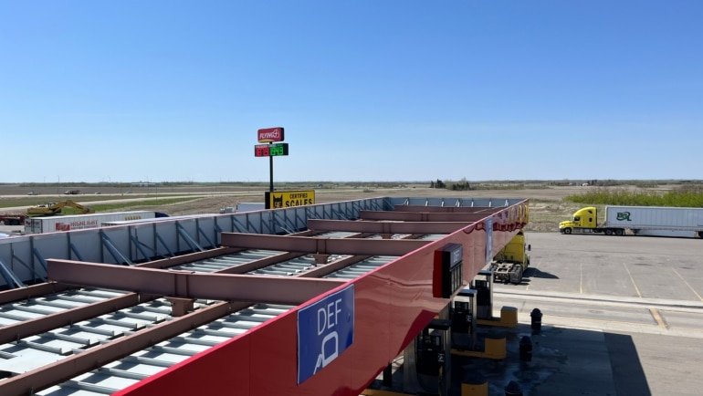 Lamar Travel Plaza highway rest stop with fuel station, parking, and travelers resting during a road trip