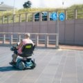 Lightweight portable travel disability scooter used by a traveler outdoors for easy and independent mobility