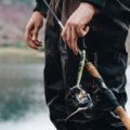 Angler holding a compact 4 piece spinning fishing rod while fishing in a scenic outdoor location