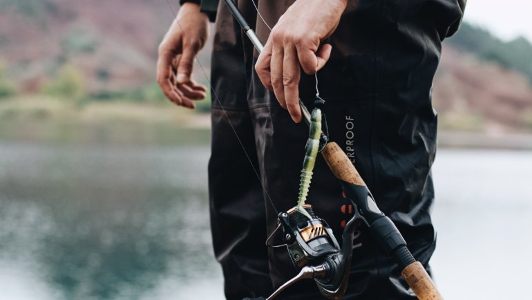 Angler holding a compact 4 piece spinning fishing rod while fishing in a scenic outdoor location