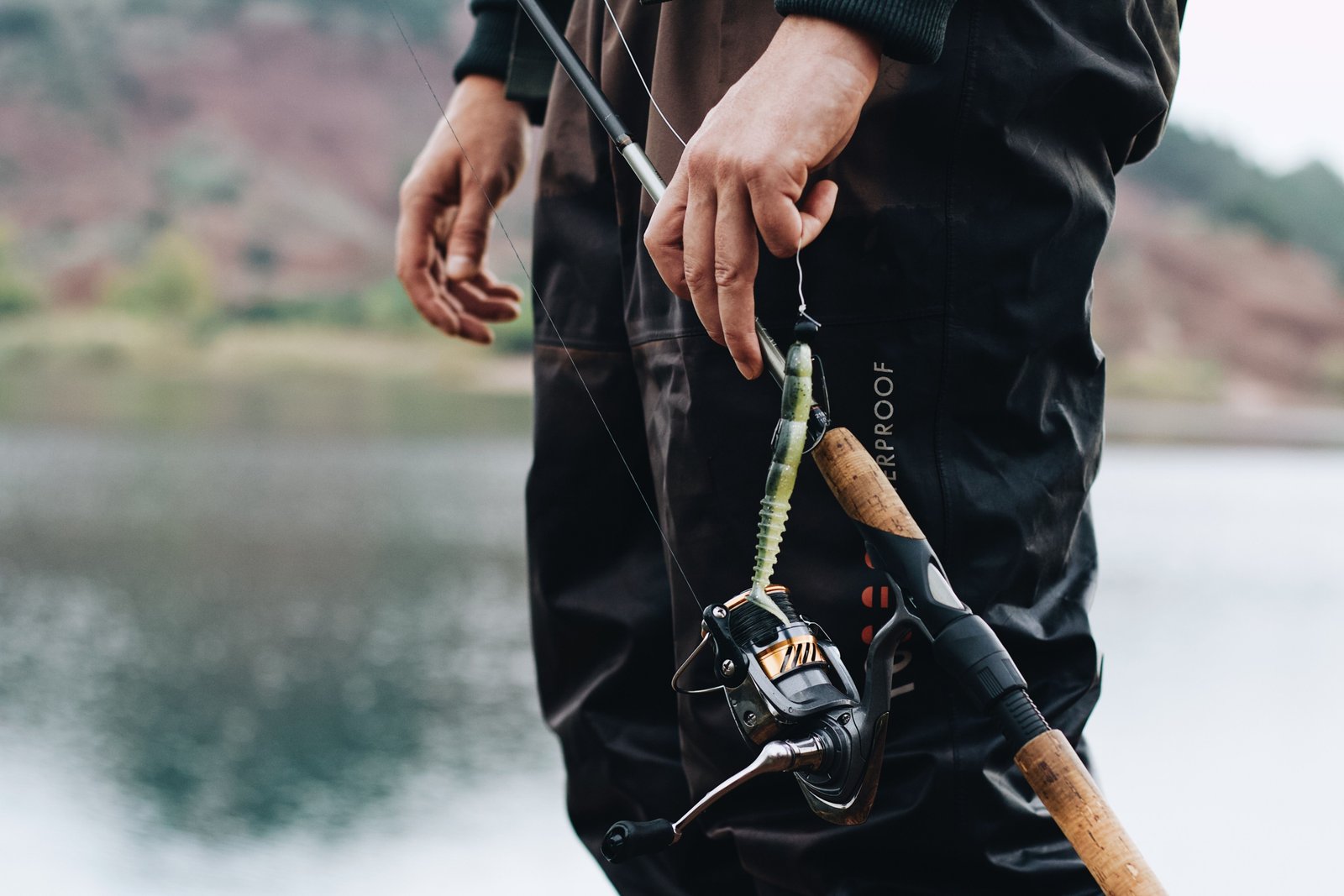 Angler holding a compact 4 piece spinning fishing rod while fishing in a scenic outdoor location