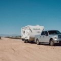 Lightweight toy hauler travel trailer parked outdoors with motorcycles, showcasing compact living and garage space for outdoor adventures