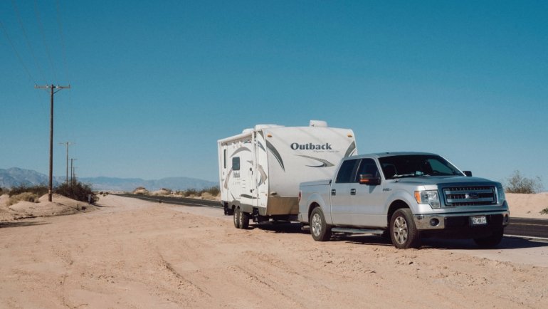 Lightweight toy hauler travel trailer parked outdoors with motorcycles, showcasing compact living and garage space for outdoor adventures