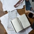 Person planning a trip on laptop with travel maps and guides for flight, accommodation, and itinerary organization
