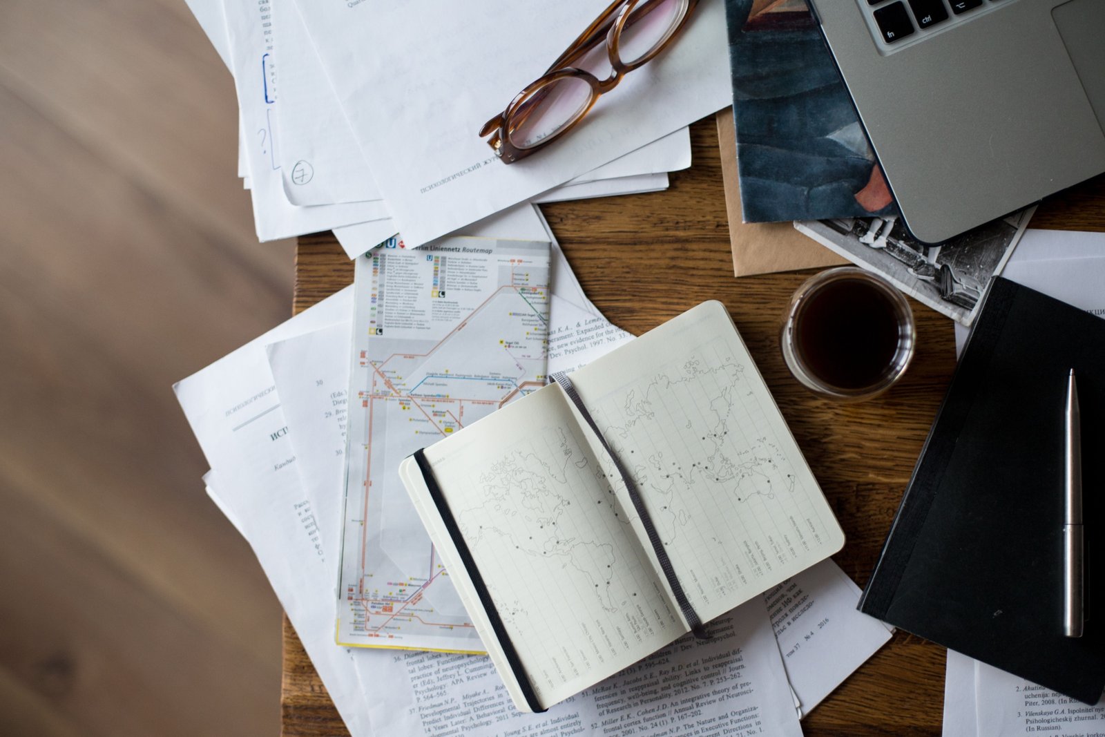 Person planning a trip on laptop with travel maps and guides for flight, accommodation, and itinerary organization