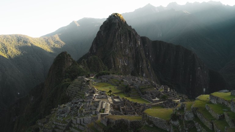Breathtaking sunrise view of Machu Picchu ancient Inca ruins surrounded by green mountains in Peru