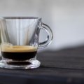 Insulated espresso travel mug held outdoors by traveler enjoying fresh coffee on the go