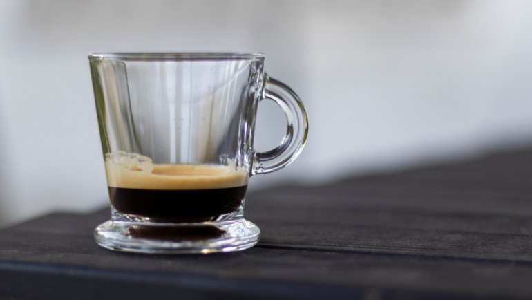 Insulated espresso travel mug held outdoors by traveler enjoying fresh coffee on the go