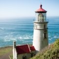 Scenic view of Oregon Coast beach with lighthouse and dramatic cliffs under clear sky