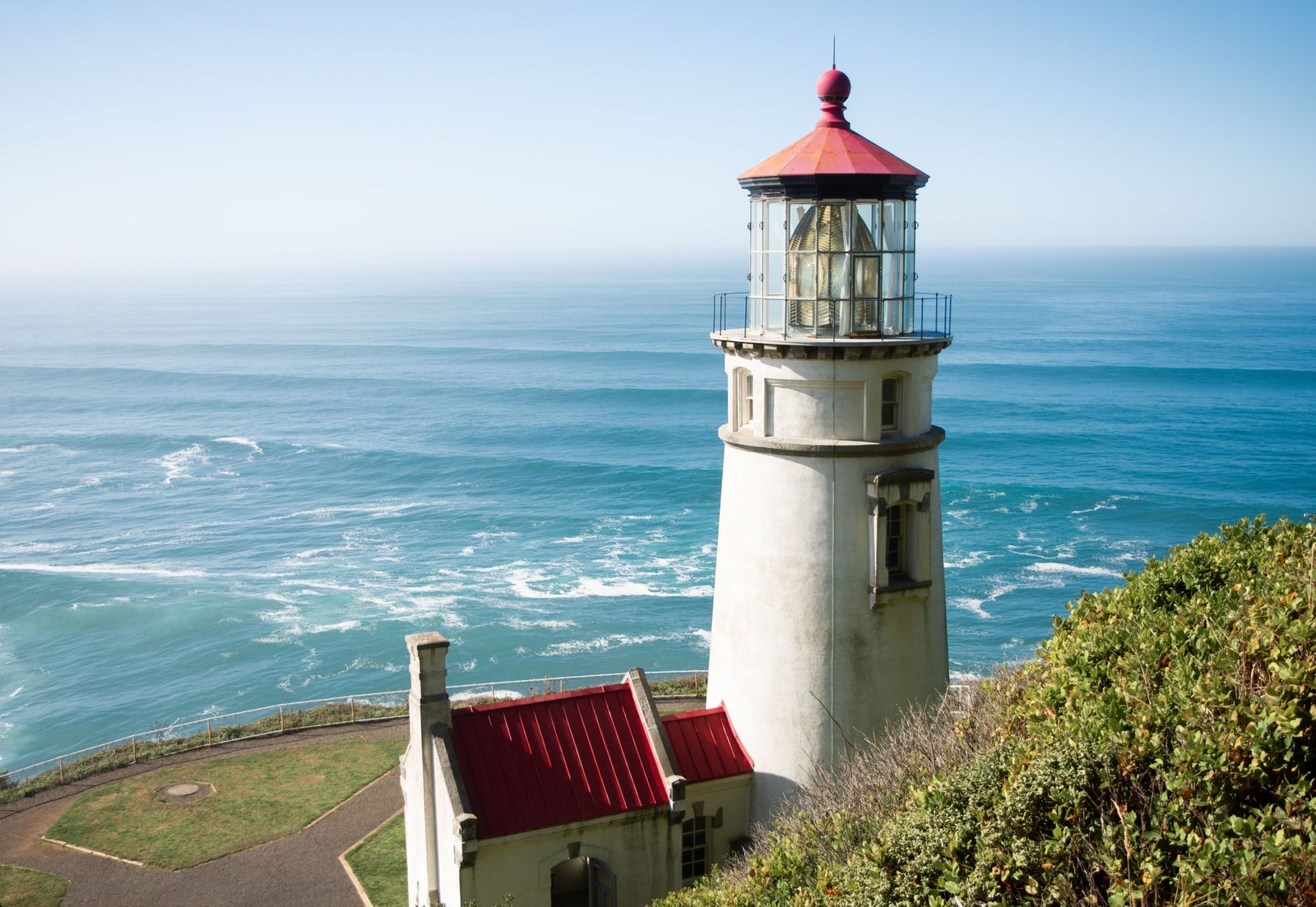 Scenic view of Oregon Coast beach with lighthouse and dramatic cliffs under clear sky