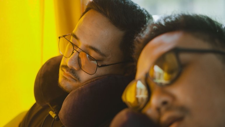 Traveler using a travel wedge pillow for neck and back support during a long flight for better comfort and posture
