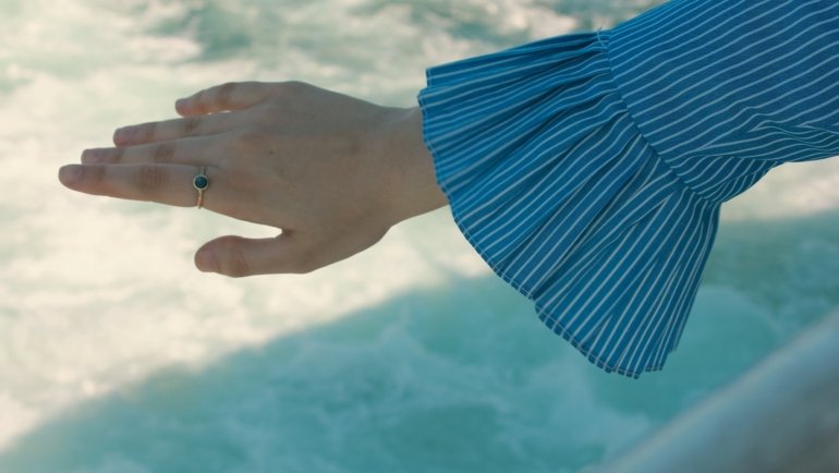 Close-up of a woman’s hand wearing a sparkling moissanite travel ring while exploring a new destination