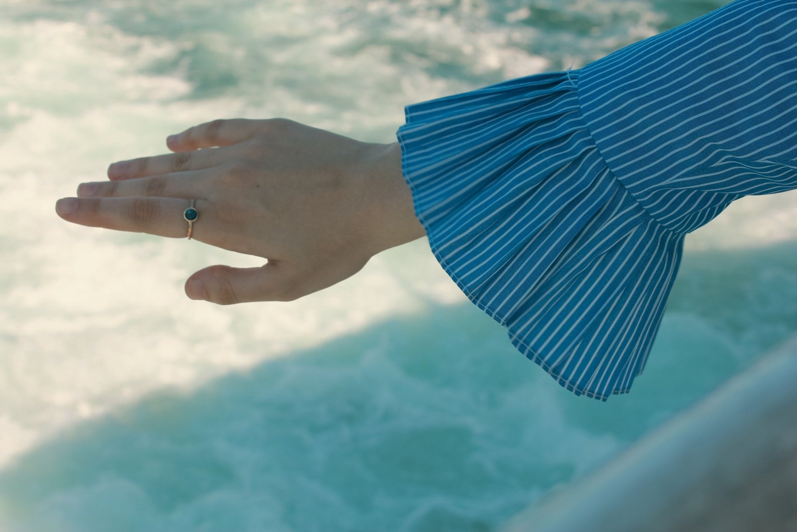 Close-up of a woman’s hand wearing a sparkling moissanite travel ring while exploring a new destination