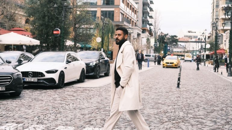 Man wearing a stylish men's travel coat in a city street showcasing comfort, style, and weather protection