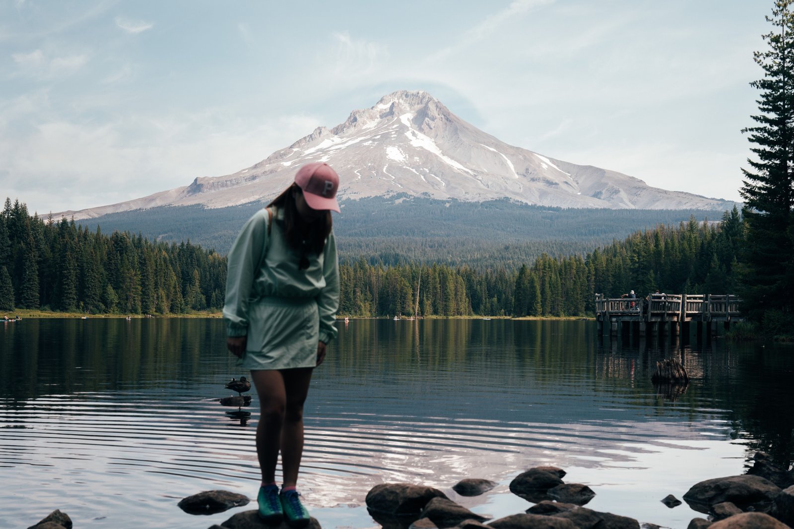 Travel nurse standing outdoors with Oregon landscape and hospital in background, representing travel nursing career and adventure