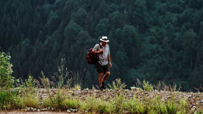 Man wearing lightweight breathable travel shorts hiking outdoors on a sunny day