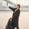 Traveler happily using smartphone to book a discounted trip with travel promo code