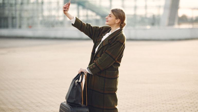 Traveler happily using smartphone to book a discounted trip with travel promo code