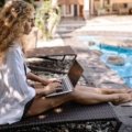Travel agent working remotely with laptop and travel materials showcasing flexible lifestyle and passion for helping clients plan trips