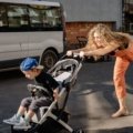 Parent pushing Joie stroller travel system with baby outdoors in a park