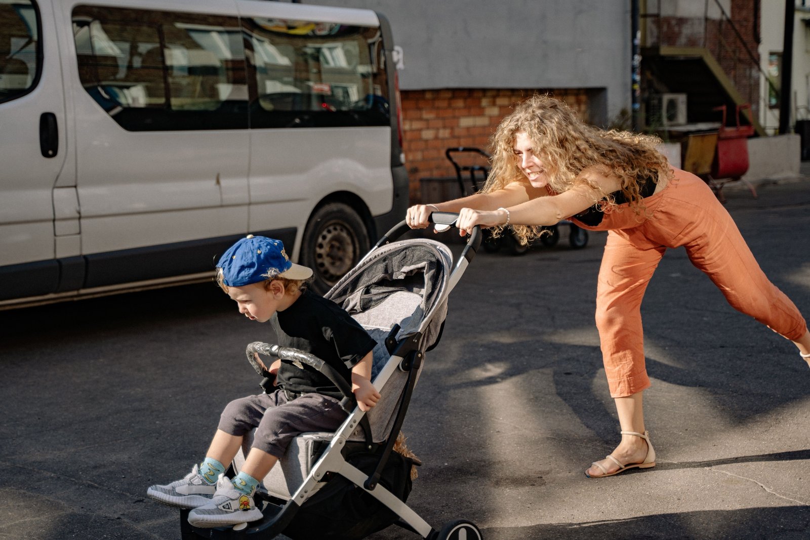 Parent pushing Joie stroller travel system with baby outdoors in a park