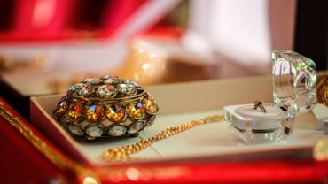 Luxury travel jewelry case open with compartments holding necklaces, rings, and bracelets on a soft velvet interior