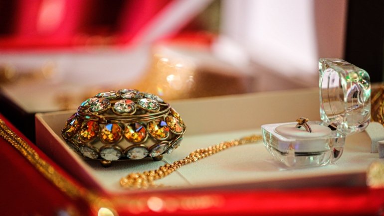 Luxury travel jewelry case open with compartments holding necklaces, rings, and bracelets on a soft velvet interior