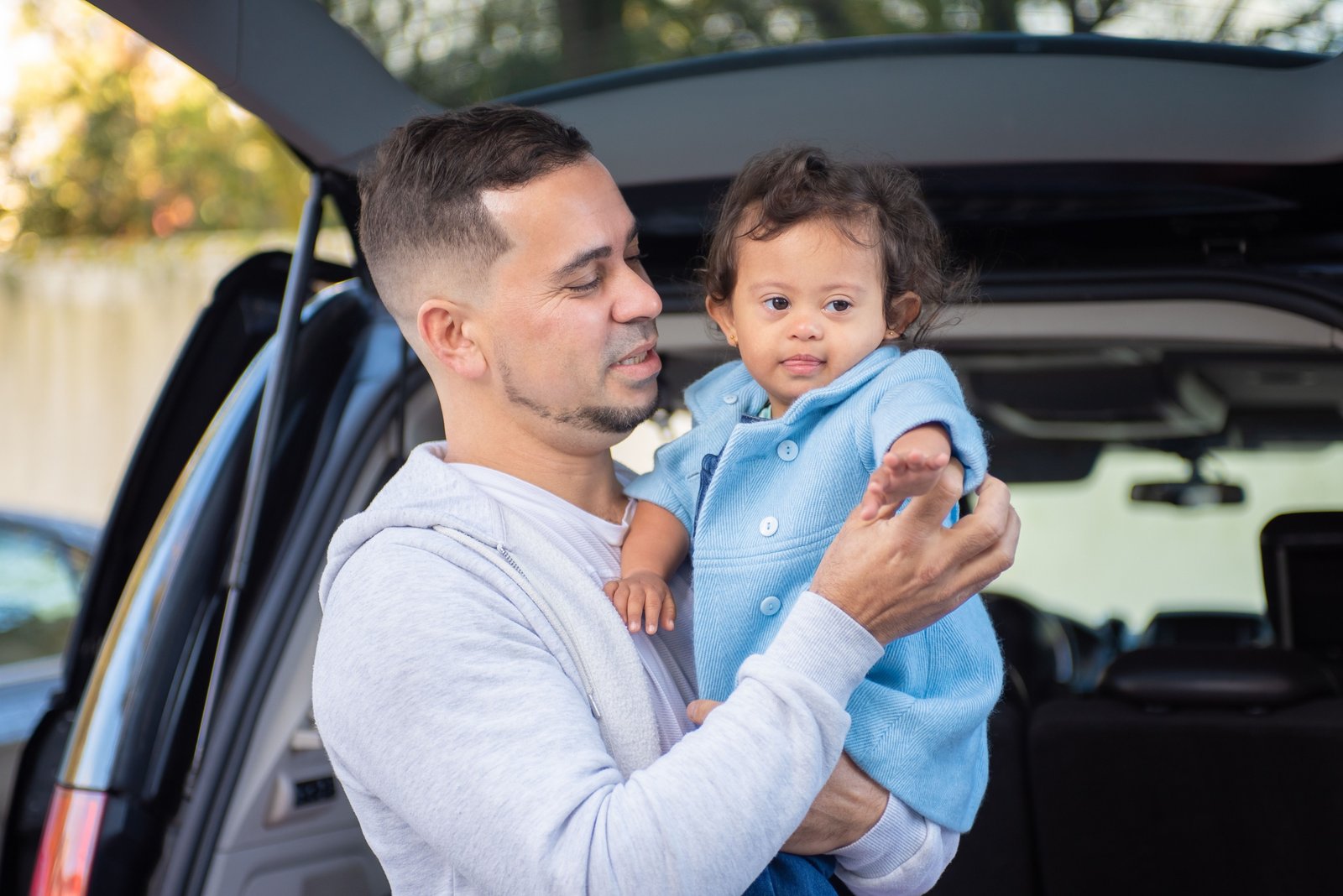 Parent carrying a padded travel bag protecting a baby car seat during family trip