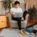 Traveler planning a trip online using Globequest Travel platform on laptop, surrounded by travel materials