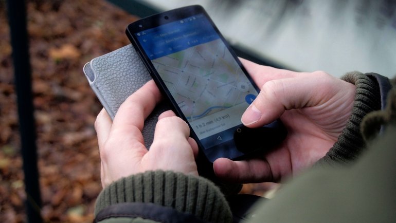 Traveler checking smartphone data usage outdoors to manage mobile internet while navigating and communicating during trip